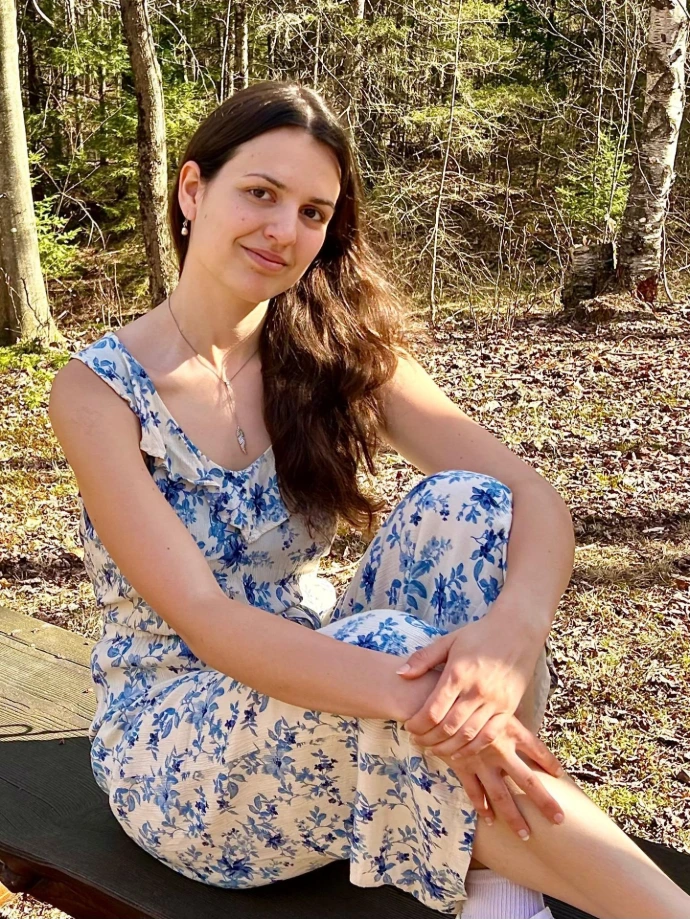 Photo d'Aglaé assise de manière décontractée sur un banc dans un parc