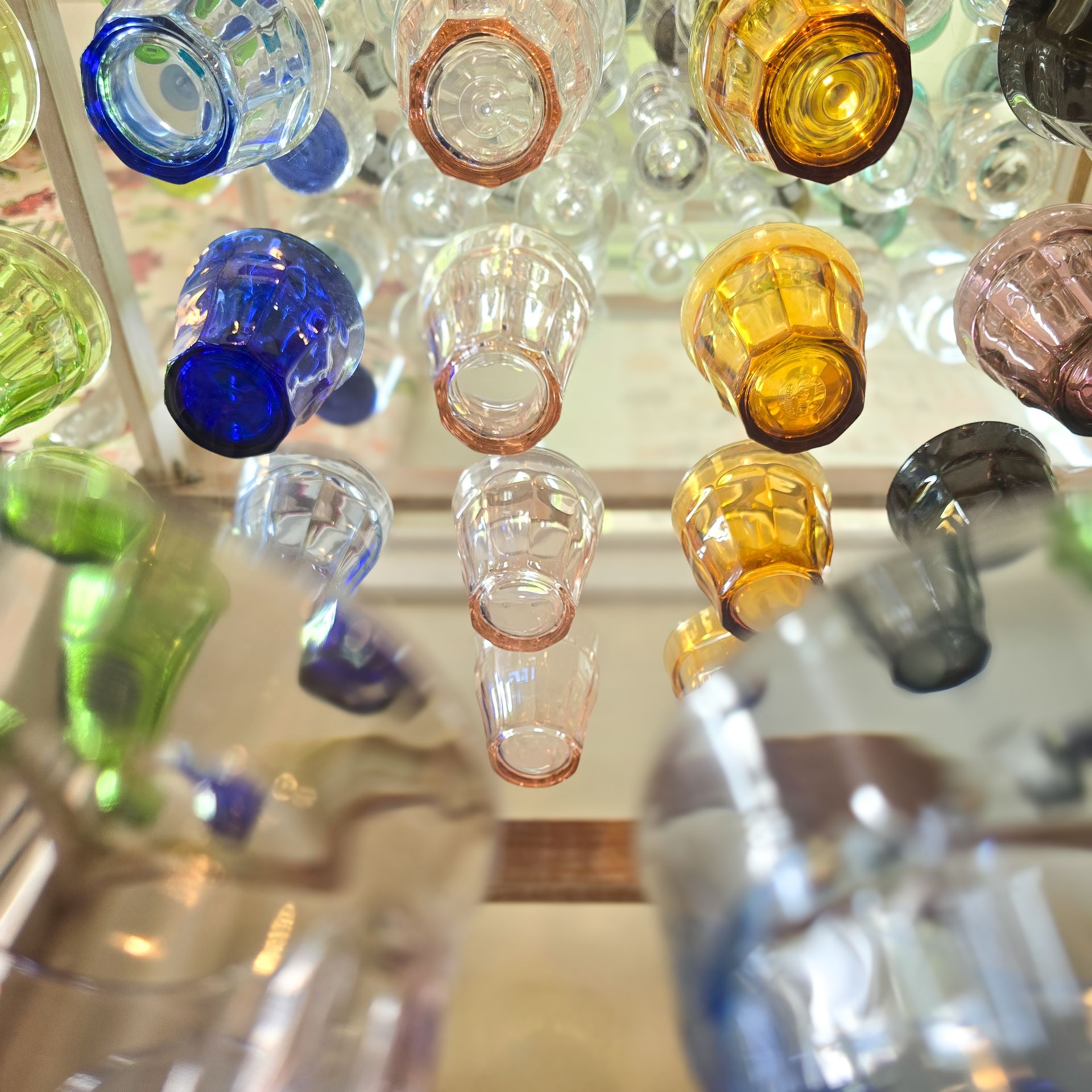 Photographie originale vue du dessous d'une étagère remplie de verres colorés